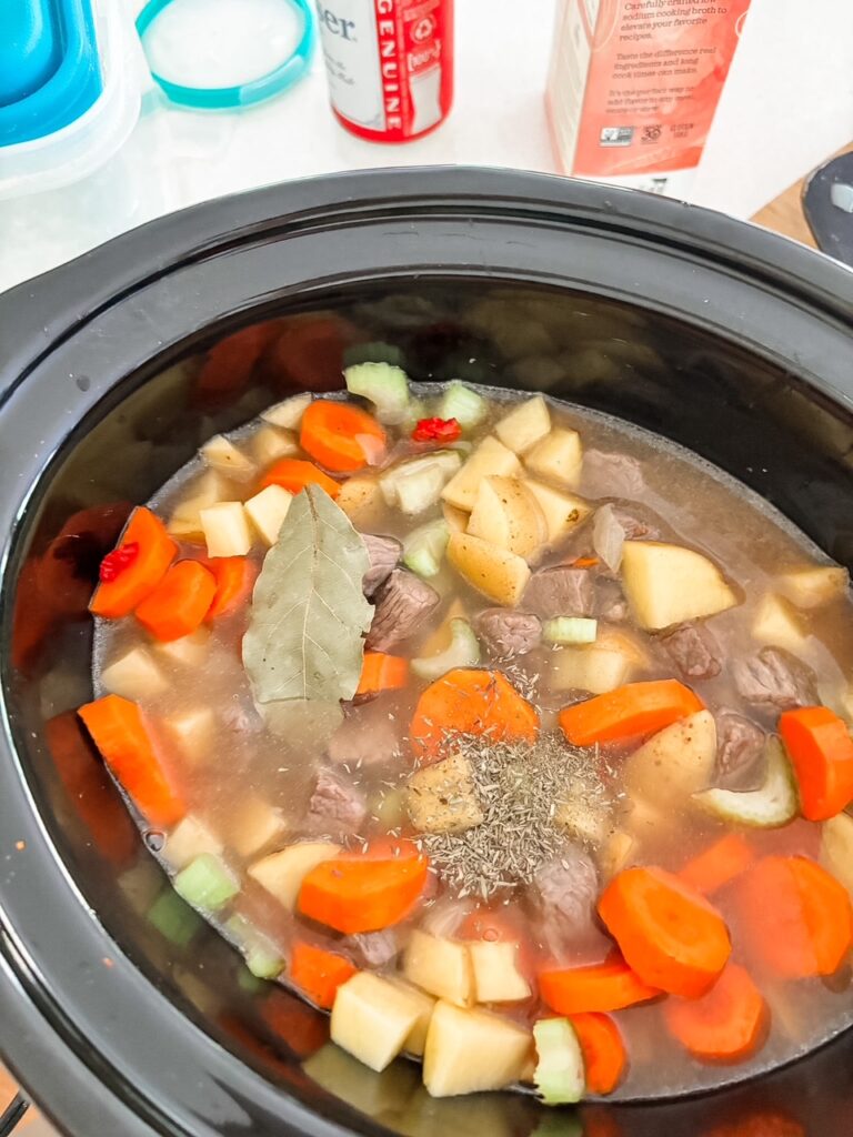 Beef, potatoes, carrots, celery, and sun-dried tomatoes in a slow cooker before cooking