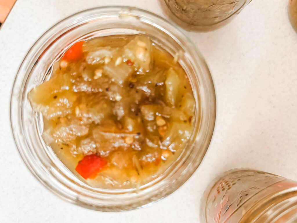 Jars of homemade green tomato sweet relish with diced green tomatoes and red bell peppers