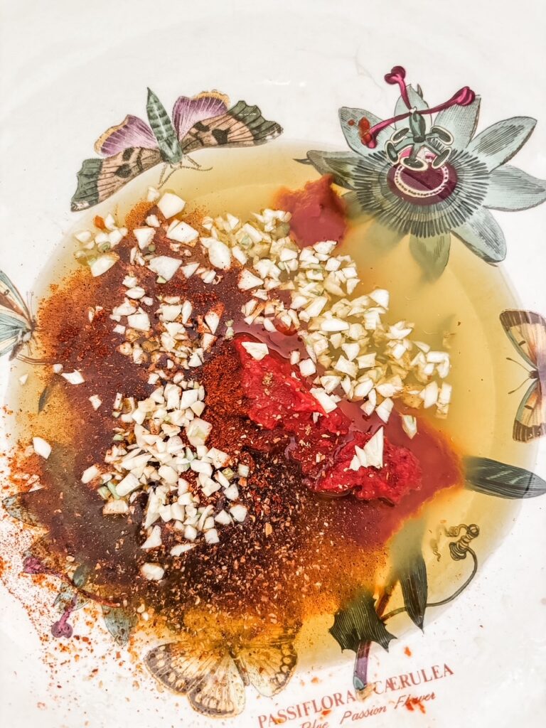 Whisking together the smoky tomato rub with olive oil, lemon juice, tomato paste, garlic, cumin, and smoked paprika in a bowl